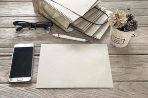 Marrone lettera avvolgere con penna, secchio, smartphone, borsa, occhiali su di legno tavolo foto