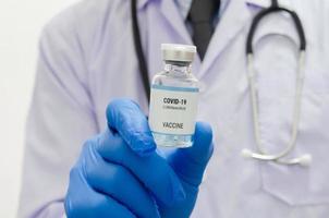 maschio medico indossare uniforme medico guanti Tenere un' bottiglia di covid 19 vaccino virus su bianca sfondo.copia spazio. foto