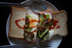 panini con uovo, prosciutto e crostini formaggio fritte nel bianca piatto foto