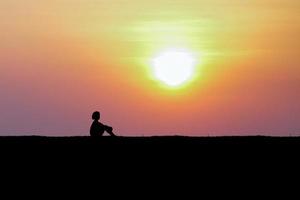 bambino seduta su piccolo collina nel tramonto tempo foto