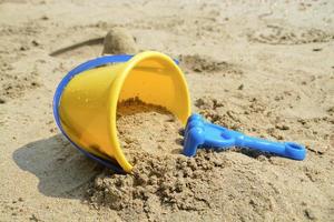 blu erpice e giallo secchio bambini giocattolo impostato per giocare sabbia su il spiaggia. vacanze con bambini a il mare. foto
