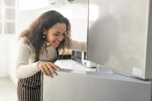 donna latina apre frigorifero o frigorifero foto