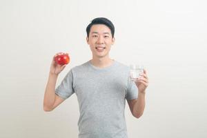 giovane uomo asiatico con bicchiere d'acqua e mela a portata di mano foto
