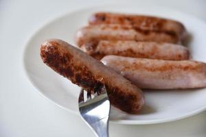 fritte carne salsicce su un' bianca piatto con un' forchetta. delizioso prima colazione di salsicce. foto