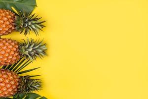 bellissimo ananas su tropicale palma Monstera le foglie isolato su luminosa pastello arancia giallo sfondo, superiore Visualizza, piatto posizione, alto sopra estate frutta. foto