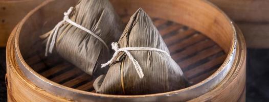 gnocco di riso, zongzi - gnocco di riso cinese zongzi su sfondo di mattoni neri tavolo in ardesia, concetto di cibo tradizionale festival della barca del drago, primo piano. foto