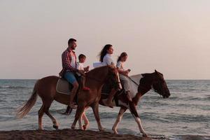 il famiglia spende tempo con loro bambini mentre equitazione cavalli insieme su un' sabbioso spiaggia. selettivo messa a fuoco foto