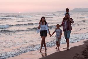 famiglia raduni e socializzazione su il spiaggia a tramonto. il famiglia passeggiate lungo il sabbioso spiaggia. selettivo messa a fuoco foto