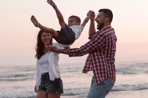 il famiglia gode loro vacanza come essi camminare il sabbioso spiaggia con loro figlio. selettivo messa a fuoco foto