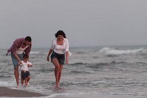 il famiglia gode loro vacanza come essi camminare il sabbioso spiaggia con loro figlio. selettivo messa a fuoco foto