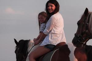 madre e figlia godere equitazione cavalli insieme di il mare. selettivo messa a fuoco foto