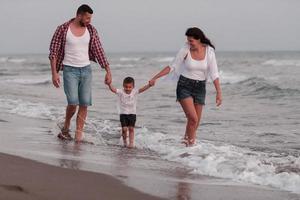 il famiglia gode loro vacanza come essi camminare il sabbioso spiaggia con loro figlio. selettivo messa a fuoco foto