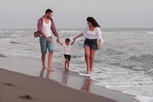 il famiglia gode loro vacanza come essi camminare il sabbioso spiaggia con loro figlio. selettivo messa a fuoco foto