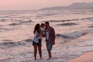 il famiglia gode loro vacanza come essi camminare il sabbioso spiaggia con loro figlio. selettivo messa a fuoco foto