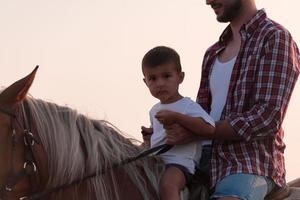 padre e figlio godere equitazione cavalli insieme di il mare. selettivo messa a fuoco foto