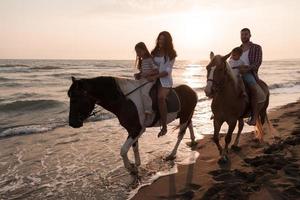 il famiglia spende tempo con loro bambini mentre equitazione cavalli insieme su un' sabbioso spiaggia. selettivo messa a fuoco foto