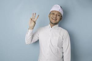 eccitato balinese uomo indossare udeng o tradizionale fascia per capelli e bianca camicia dando numero 12345 di mano gesto foto