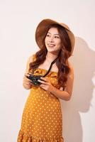attraente giovane donna con un' foto telecamera nel sua mano su un isolato beige sfondo. il concetto viaggio
