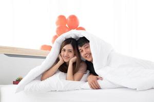 un' contento giovane coppie siamo nel letto sotto il coperta dopo scia su nel San Valentino giorno mattina nel loro Camera da letto. foto