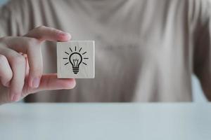 ispirazione, di brainstorming creativo idee per nuovo innovazioni. mano Tenere creativo leggero lampadina icone su legna cubo, analisi soluzione e sviluppo, moderno attività commerciale, innovativo di nuovo idee. foto