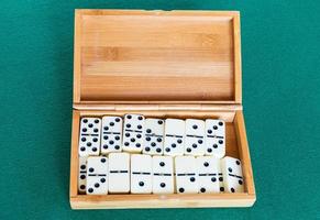 impostato di bianca domino piastrelle nel bambù scatola su tavolo foto