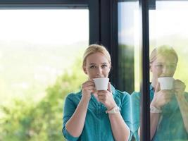 giovane donna potabile mattina caffè di il finestra foto