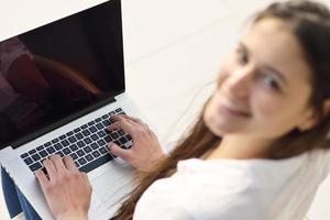 rilassato giovane donna a casa Lavorando su il computer portatile computer foto