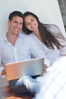 giovane coppia utilizzando il computer portatile a casa foto