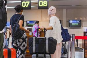 Due donna viaggiatori con viso maschera dai un'occhiata nel a il aeroporto. foto