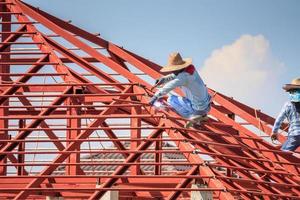 lavoratori del saldatore che installano la struttura del telaio in acciaio del tetto della casa in un cantiere edile foto