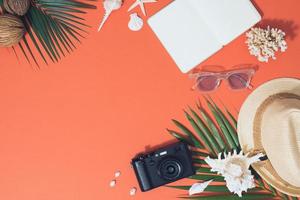 colorato estate vacanze moda piatto posare - cannuccia cappello, telecamera, occhiali da sole, mare conchiglie su luminosa arancia sfondo foto