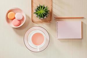 styled azione fotografia beige ufficio scrivania tavolo con vuoto taccuino, amaretto, forniture e caffè tazza foto