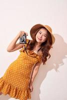 Immagine di giovane fotografo donna isolato al di sopra di beige sfondo parete Tenere telecamera. foto