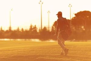 giocatore a piedi e trasporto golf Borsa a bellissimo tramonto foto