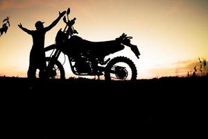 sagome maschili e moto da cross da turismo. parco per rilassarsi in montagna la sera. concetto di viaggio avventura e tempo libero foto