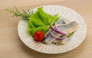 filetto di aringa sul piatto e fondo di legno foto