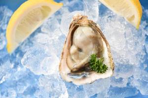 fresco Ostriche frutti di mare su ghiaccio sfondo - Aperto ostrica conchiglia con erba spezie Limone prezzemolo servito tavolo e salutare mare cibo crudo ostrica cena nel il ristorante buongustaio cibo foto