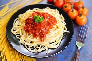 spaghetti bolognese spaghetti italiano pasta servito su nero piatto con pomodoro e prezzemolo nel il ristorante italiano cibo e menù foto