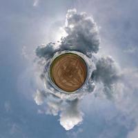 piccolo pianeta nel cielo blu con bellissime nuvole. trasformazione del panorama sferico a 360 gradi. vista aerea astratta sferica. curvatura dello spazio. foto