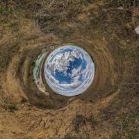 palla di cielo blu nel mezzo del campo vorticoso. inversione del minuscolo pianeta trasformazione del panorama sferico a 360 gradi. curvatura dello spazio. foto