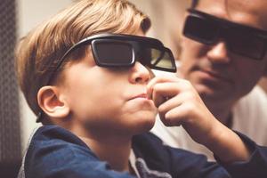 piccolo ragazzo con 3d bicchieri mangiare Popcorn durante film volta. foto