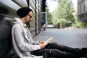 lato Visualizza di un' uomo lettura un' libro su un' marciapiede. foto