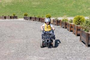 contento ragazzo guida quad su un' via strada sentiero. foto