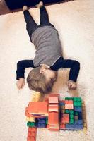 piccolo ragazzo rilassante su tappeto dopo giocando con plastica giocattolo blocchi. foto