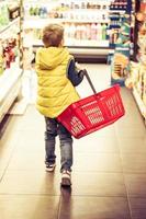 posteriore Visualizza di ragazzo acquisto drogheria a supermercato. foto