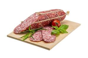 salame su di legno piatto e bianca sfondo foto