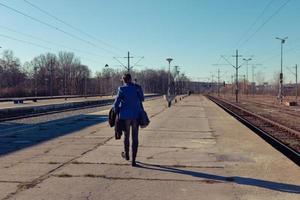 posteriore Visualizza di uomo a piedi a Ferrovia stazione piattaforma. foto