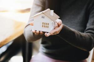 femmina mano Tenere un' Casa modello, assicurazione concetto e casa prestito. foto