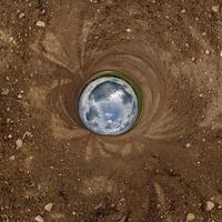 sfera blu piccolo pianeta all'interno della strada sterrata o dello sfondo del campo. foto