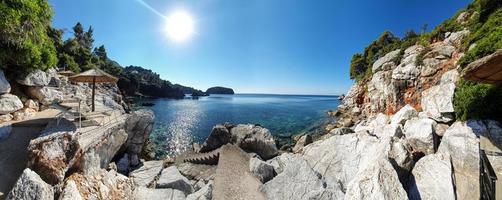 vista panoramica della baia incontaminata di un'isola greca con lettini e ombrelloni vuoti. foto